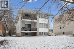 Snow covered rear of property with a balcony and brick siding - 