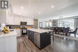 Kitchen with appliances with stainless steel finishes, white cabinets, a kitchen island, light stone countertops, and a breakfast bar area - 