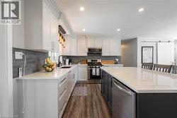 Kitchen featuring appliances with stainless steel finishes, light stone counters, white cabinetry, a barn door, and recessed lighting - 