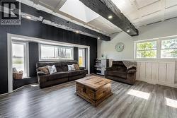 Living room with wood walls, wood finished floors, coffered ceiling, and a decorative wall - 