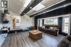 Living room with arched walkways, coffered ceiling, wood finished floors, a decorative wall, and a wainscoted wall - 