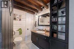 Bathroom with vanity, beamed ceiling, wooden walls, and light marble finish flooring - 