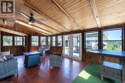 Living area featuring wood walls, wooden ceiling, wood-type flooring, and a ceiling fan - 