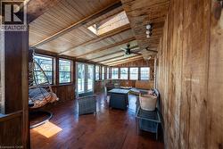 Living area featuring wood walls, a skylight, wooden ceiling, dark wood-type flooring, and ceiling fan - 