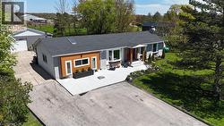 View of front of home with roof with shingles, a front lawn, driveway, a garage, and view of scattered trees - 