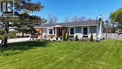 View of front facade with brick siding, a porch, a chimney, and a shingled roof - 