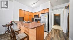 Kitchen featuring a peninsula, stainless steel appliances, dark wood-type flooring, brown cabinets, and a breakfast bar area - 
