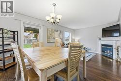 Dining space with dark wood-style floors, a glass covered fireplace, and a chandelier - 
