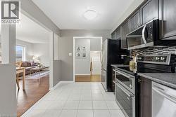 Kitchen with stainless steel appliances, light tile patterned floors, tasteful backsplash, and dark countertops - 