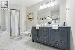 Bathroom featuring tiled tub, double vanity, light tile patterned flooring, and curtained shower - 