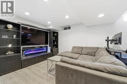 Living area with light wood-type flooring, a glass covered fireplace, and recessed lighting - 