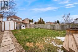 Fenced backyard featuring a storage unit and a residential view - 