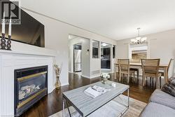 Living room with a chandelier, dark wood-type flooring, and a glass covered fireplace - 