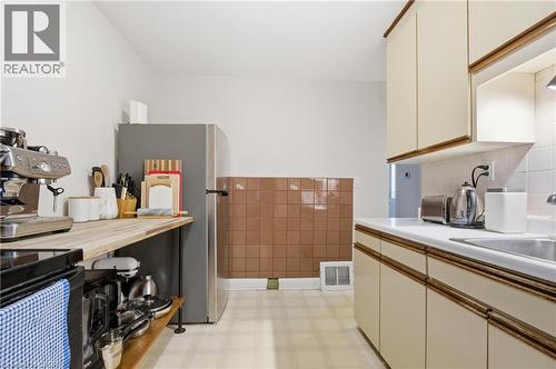 Kitchen with light flooring, light countertops, freestanding refrigerator, and cream cabinetry - 157 Bridgeport Road E, Waterloo, ON - Indoor Photo Showing Kitchen