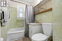 Bathroom with vanity, shower / tub combo, and tile walls - 
