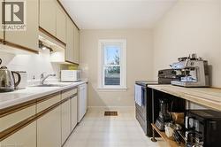 Kitchen featuring white appliances, light flooring, decorative backsplash, cream cabinets, and wood counters - 