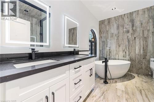 Heated flooring, touch LED vanity mirrors with dual light control, free standing tub, matching tile wall, dual vanity - 515 Hamilton Drive, Ancaster, ON - Indoor Photo Showing Bathroom