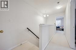 Hallway with carpet flooring, an upstairs landing, a textured ceiling, and a chandelier - 