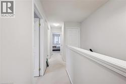 Hall featuring light carpet, an upstairs landing, and a textured ceiling - 