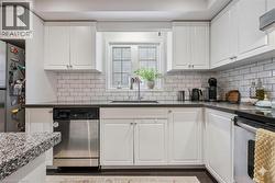 Kitchen featuring white cabinetry, stainless steel appliances, and decorative backsplash - 