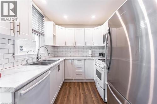 Kitchen with stainless steel appliances, white cabinetry, dark wood finished floors, light stone countertops, and recessed lighting - 140 Royal Avenue, Hamilton, ON - Indoor Photo Showing Kitchen With Double Sink With Upgraded Kitchen