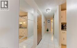 Hall featuring a textured ceiling and light tile patterned floors - 