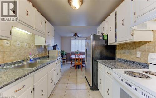 Kitchen featuring white appliances, decorative backsplash, white cabinetry, and ceiling fan - 4 Avalon Place Unit# 103, Kitchener, ON - Indoor Photo Showing Kitchen With Double Sink