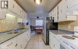 Kitchen featuring white appliances, decorative backsplash, white cabinetry, and ceiling fan - 