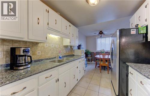 Kitchen featuring freestanding refrigerator, white cabinets, and tasteful backsplash - 4 Avalon Place Unit# 103, Kitchener, ON - Indoor Photo Showing Kitchen With Double Sink