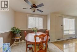 Dining space with a baseboard radiator, light tile patterned floors, and a ceiling fan - 