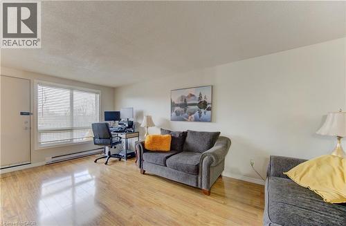 Home office featuring a textured ceiling, a baseboard heating unit, and light wood finished floors - 4 Avalon Place Unit# 103, Kitchener, ON - Indoor Photo Showing Living Room