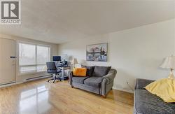 Home office featuring a textured ceiling, a baseboard heating unit, and light wood finished floors - 