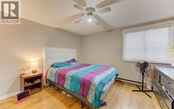 Bedroom with light wood finished floors, a ceiling fan, and a baseboard heating unit - 