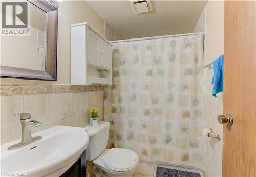 Full bath featuring vanity, tile walls, and a shower with shower curtain - 4 Avalon Place Unit# 103, Kitchener, ON - Indoor Photo Showing Bathroom