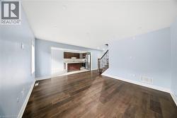 Unfurnished living room with stairway, dark wood finished floors, and recessed lighting - 