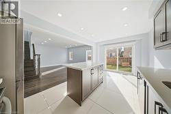 Kitchen with freestanding refrigerator, recessed lighting, a kitchen island, light tile patterned floors, and open floor plan - 