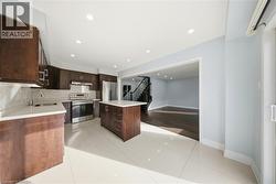 Kitchen with light tile patterned floors, dark brown cabinetry, stainless steel appliances, backsplash, and recessed lighting - 