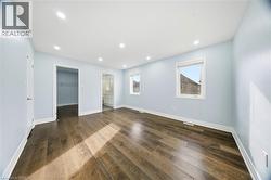 Unfurnished bedroom with a spacious closet, dark wood finished floors, recessed lighting, and ensuite bath - 