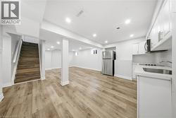 Below grade area with stairway, freestanding refrigerator, light wood-style flooring, and recessed lighting - 