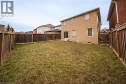 Rear view of house with brick siding and a fenced backyard - 