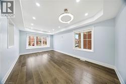 Spare room featuring dark wood-style floors, recessed lighting, and a tray ceiling - 