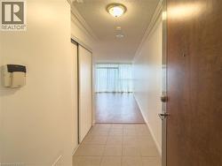 Hall featuring ornamental molding, a textured ceiling, and light tile patterned floors - 