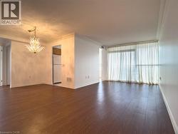 Unfurnished living room featuring crown molding, dark wood-style floors, a chandelier, and a wall of windows - 