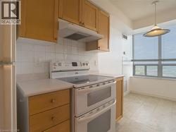 Kitchen with double oven range, under cabinet range hood, light countertops, decorative backsplash, and freestanding refrigerator - 