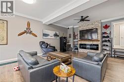 Living area with crown molding, light wood-style flooring, a ceiling fan, and a fireplace - 