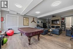 Game room with ornamental molding, billiards, light wood finished floors, a wall mounted AC, and a ceiling fan - 