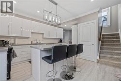 Kitchen with a kitchen breakfast bar, hanging light fixtures, a kitchen island, white cabinets, and recessed lighting - 