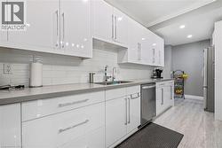 Kitchen with white cabinetry, stainless steel appliances, ornamental molding, backsplash, and recessed lighting - 