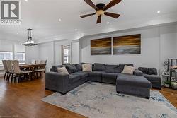 Living room featuring dark wood-type flooring, ornamental molding, recessed lighting, and ceiling fan - 