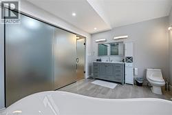 Full bathroom featuring a freestanding tub, vanity, a shower stall, recessed lighting, and wood finish floors - 
